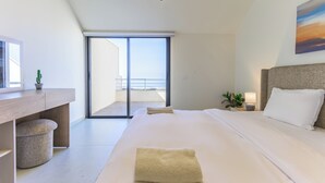 Ein modernes Hotelzimmer mit einem großen Bett, einem Schreibtisch, einer kleinen Pflanze und Blick auf den Balkon.