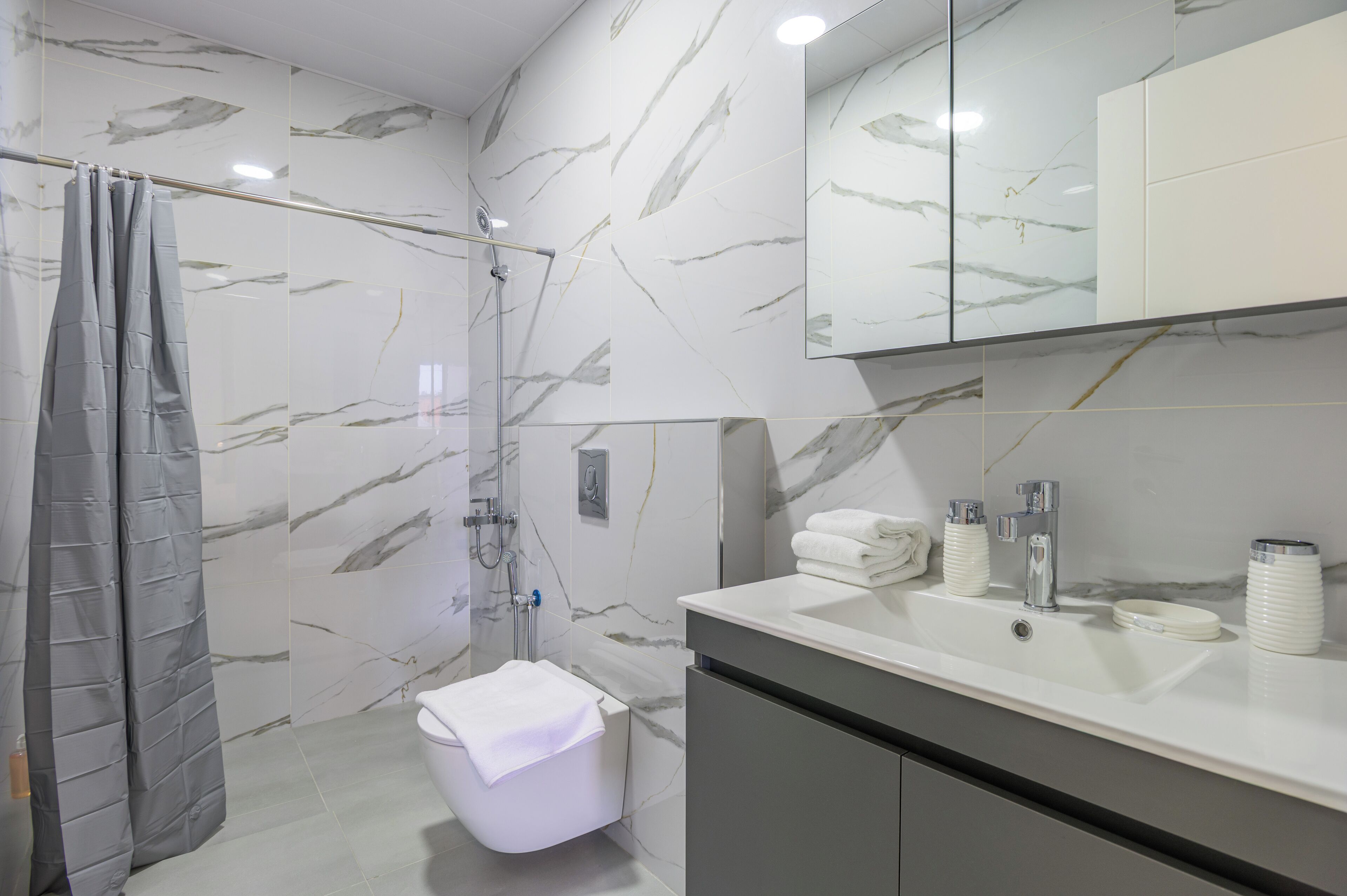 Un baño moderno con ducha, inodoro y tocador con lavabo y espejo.