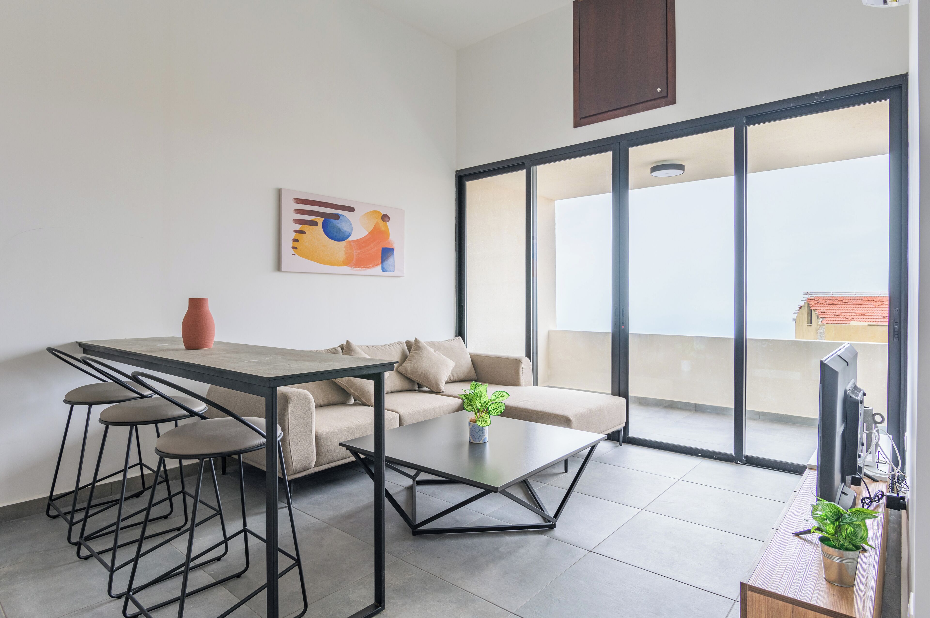 Una sala moderna con un sofá, una mesa de centro y una zona de comedor con taburetes.