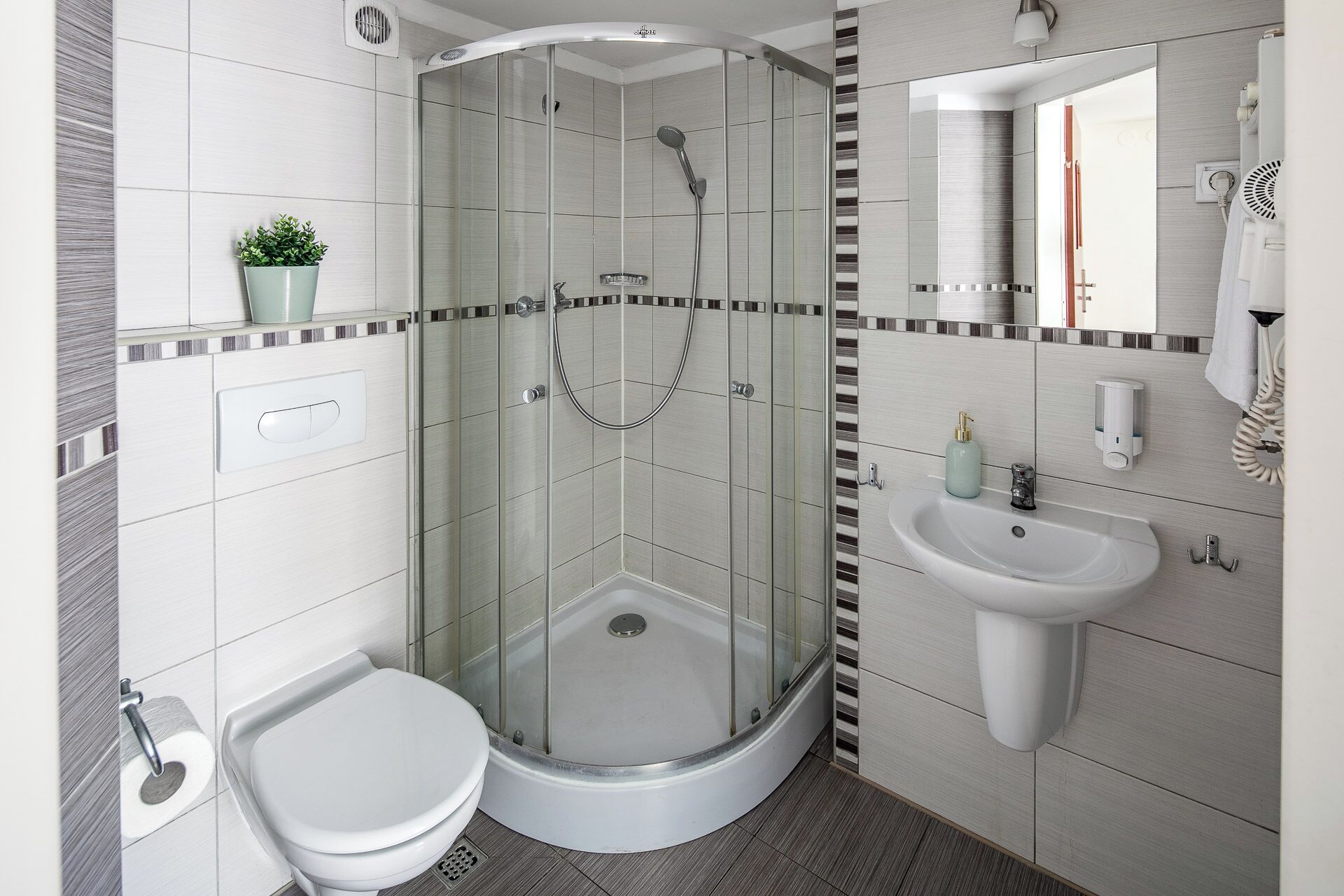 A modern bathroom with a glass-enclosed shower, a white sink, and a toilet.