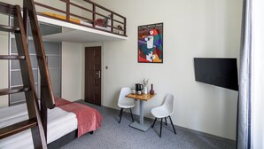 A dormitory room with a bunk bed, a desk with two chairs, a television, and a poster on the wall. - The Royal Patch Aparthotel (Kraków)
