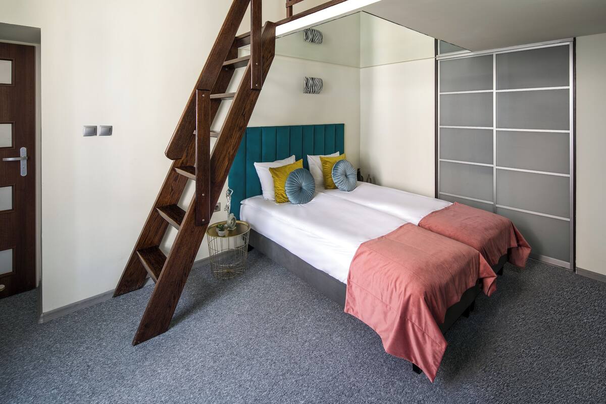 A bedroom with a bed, a wooden ladder, a wardrobe, and a small round table.