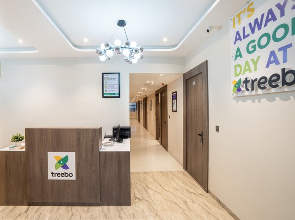 A reception desk with a logo, a hallway with doors, and a sign on the wall. - Treebo Vro Boutique, Andheri East (Mumbai)