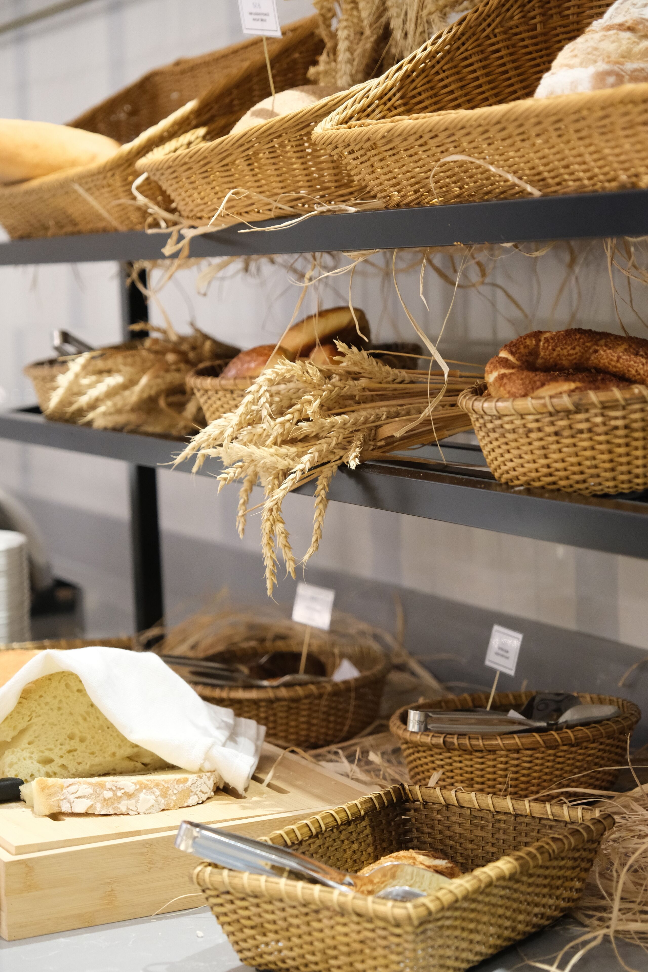 Wicker baskets containing bread and wheat on shelves.