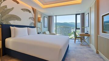 Habitación de hotel con una cama grande, un escritorio y vistas a la ciudad.