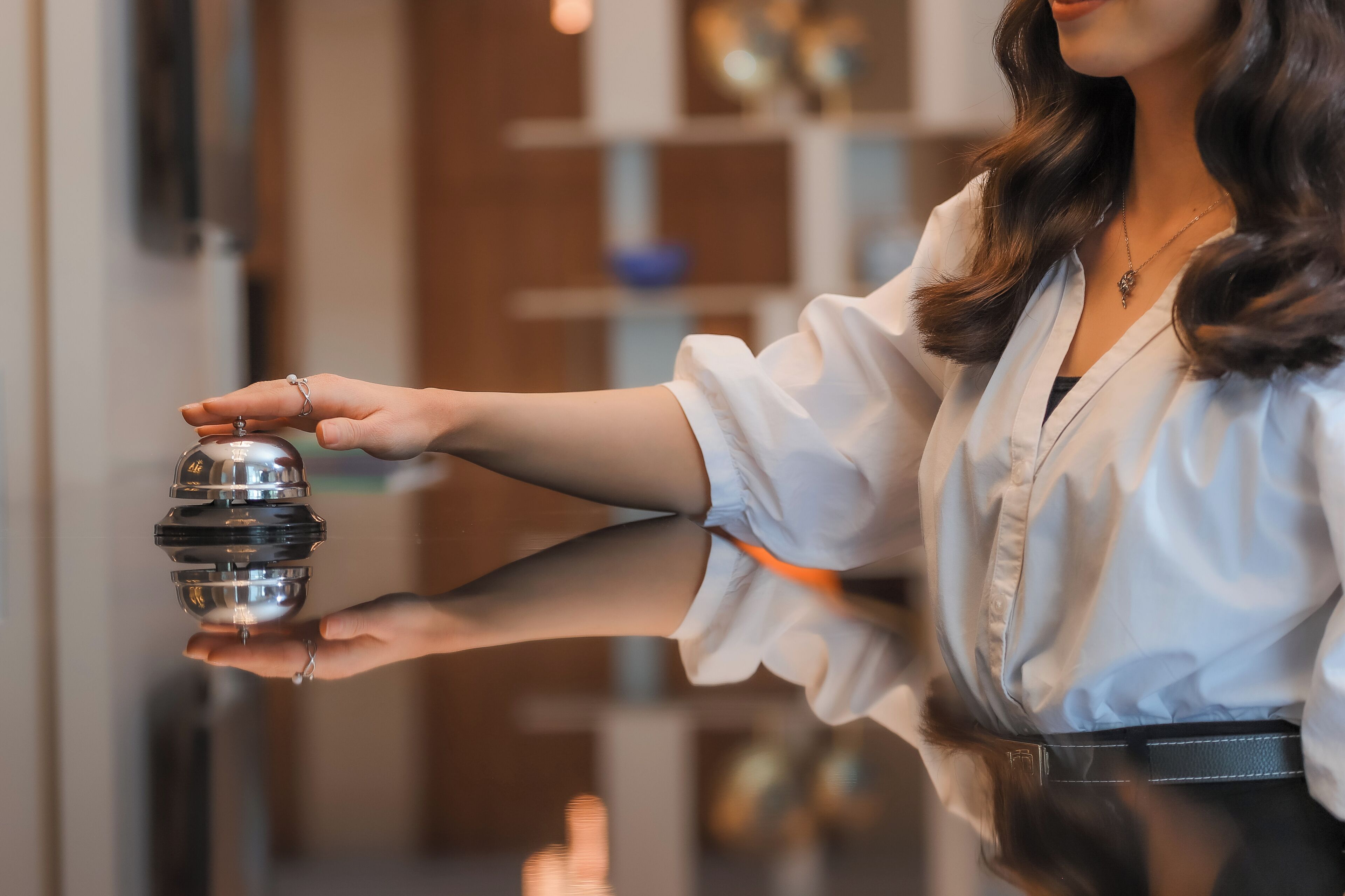 A person holding a metallic object, possibly a key or a tool, in a well-lit indoor setting with a reflective surface.