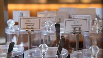 A selection of clear glass containers with metal spoons, each labeled with a name and type of jam.