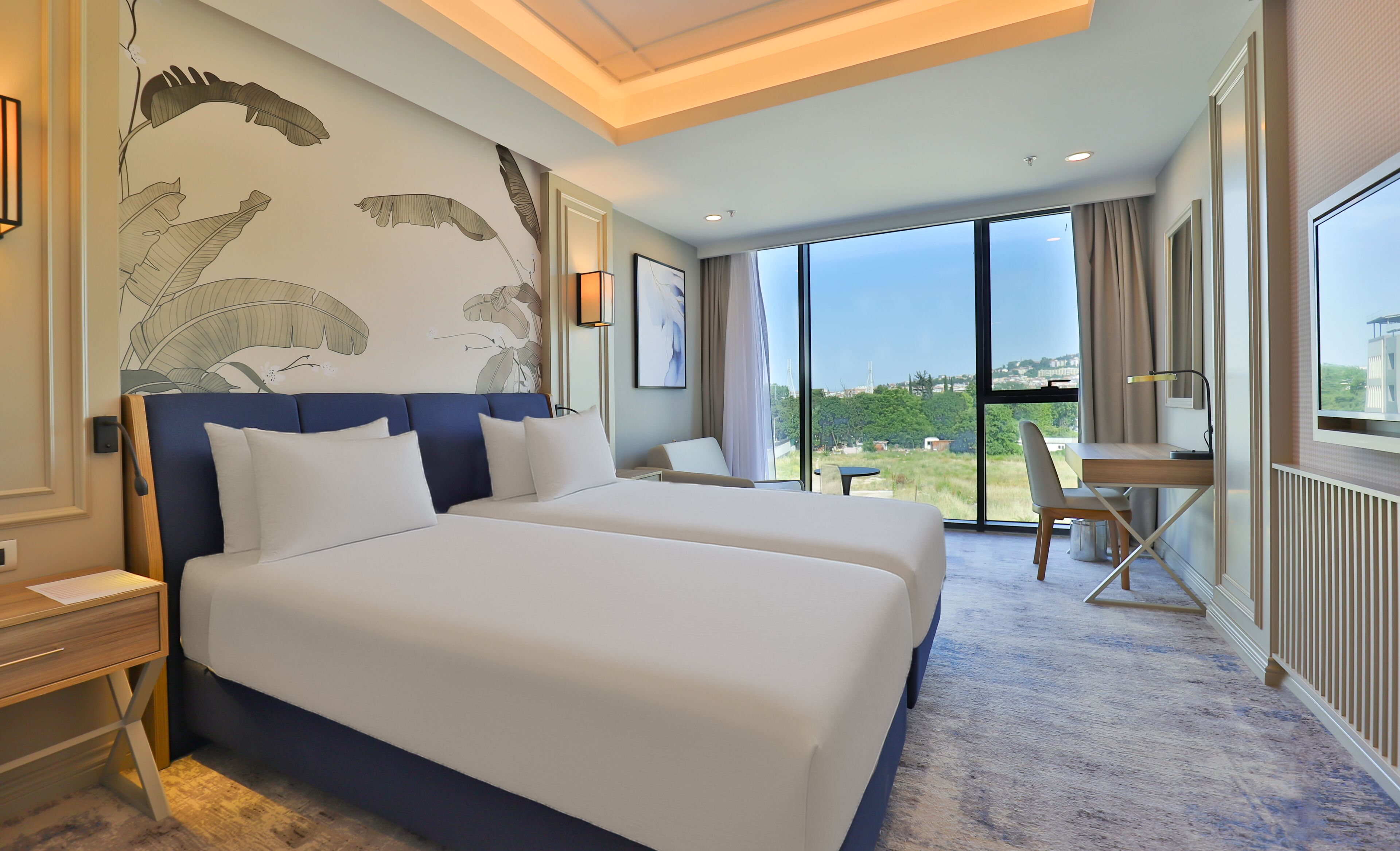 Habitación de hotel con una cama grande, un escritorio y vistas al exterior.