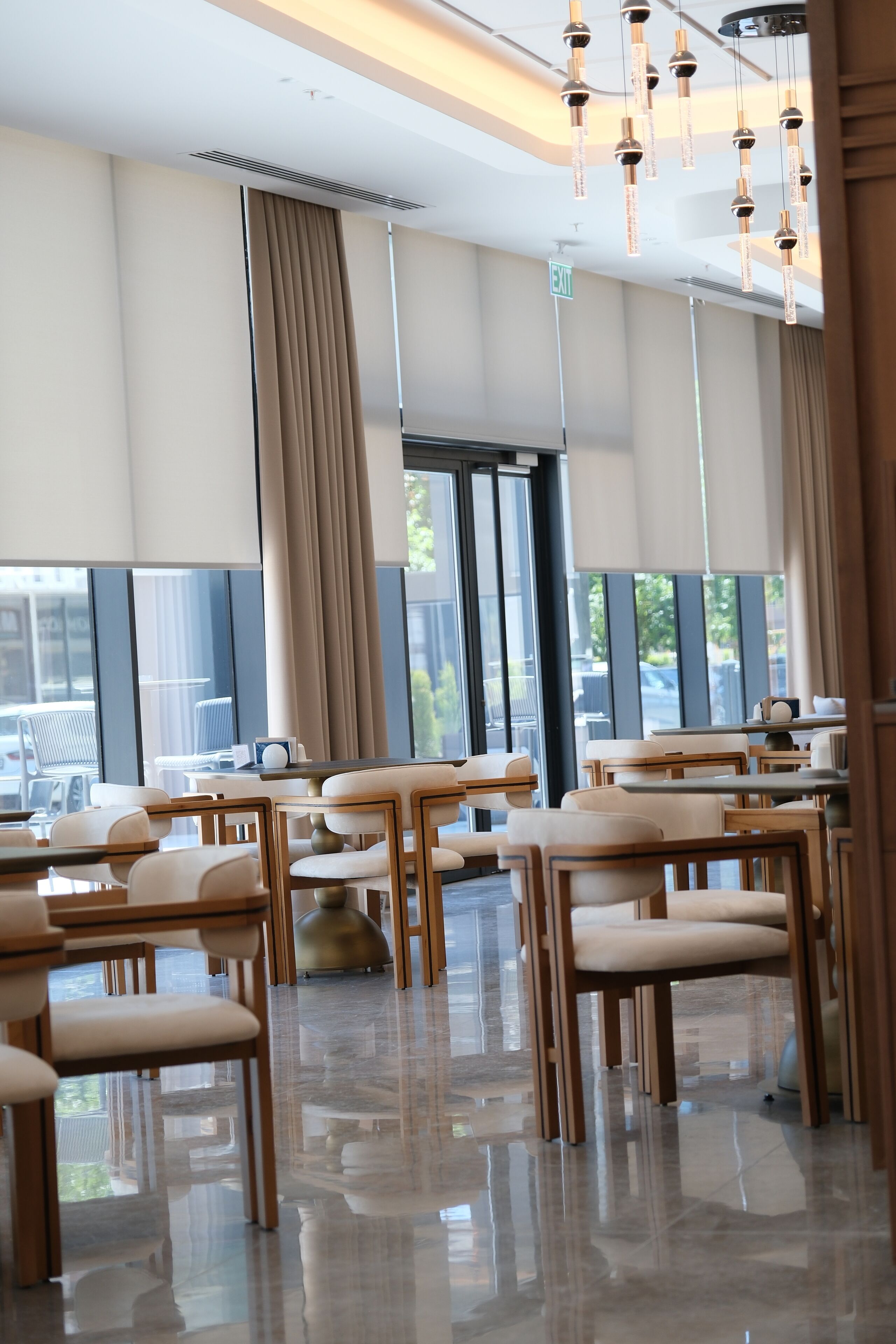 En modern restaurang med högt i tak, stora fönster och ett rent, välpolerat golv.
