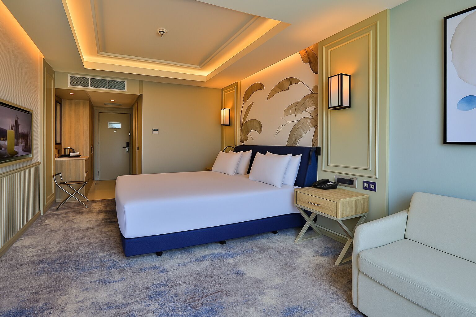 Una habitación de hotel con una cama grande, una mesita de noche con lámpara, una silla y un televisor.