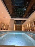 Una piscina interior moderna con un techo que simula un cielo estrellado.