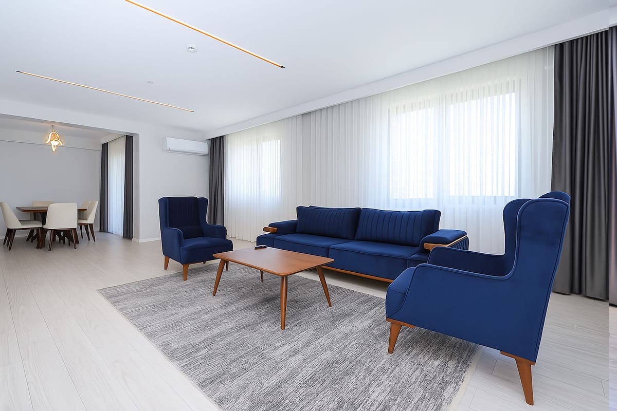 A modern living room with a sofa, two armchairs, a coffee table, and a dining area with chairs and a table.