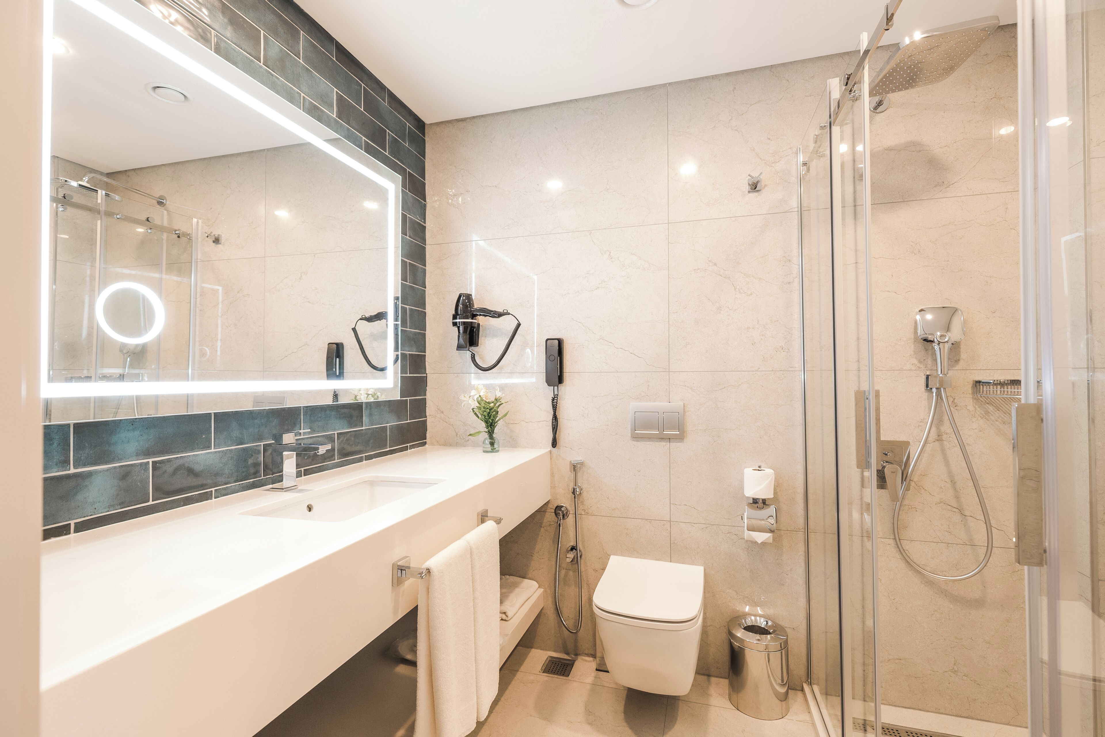 Un baño moderno con ducha envuelta en vidrio, tocador con espejo y un inodoro.