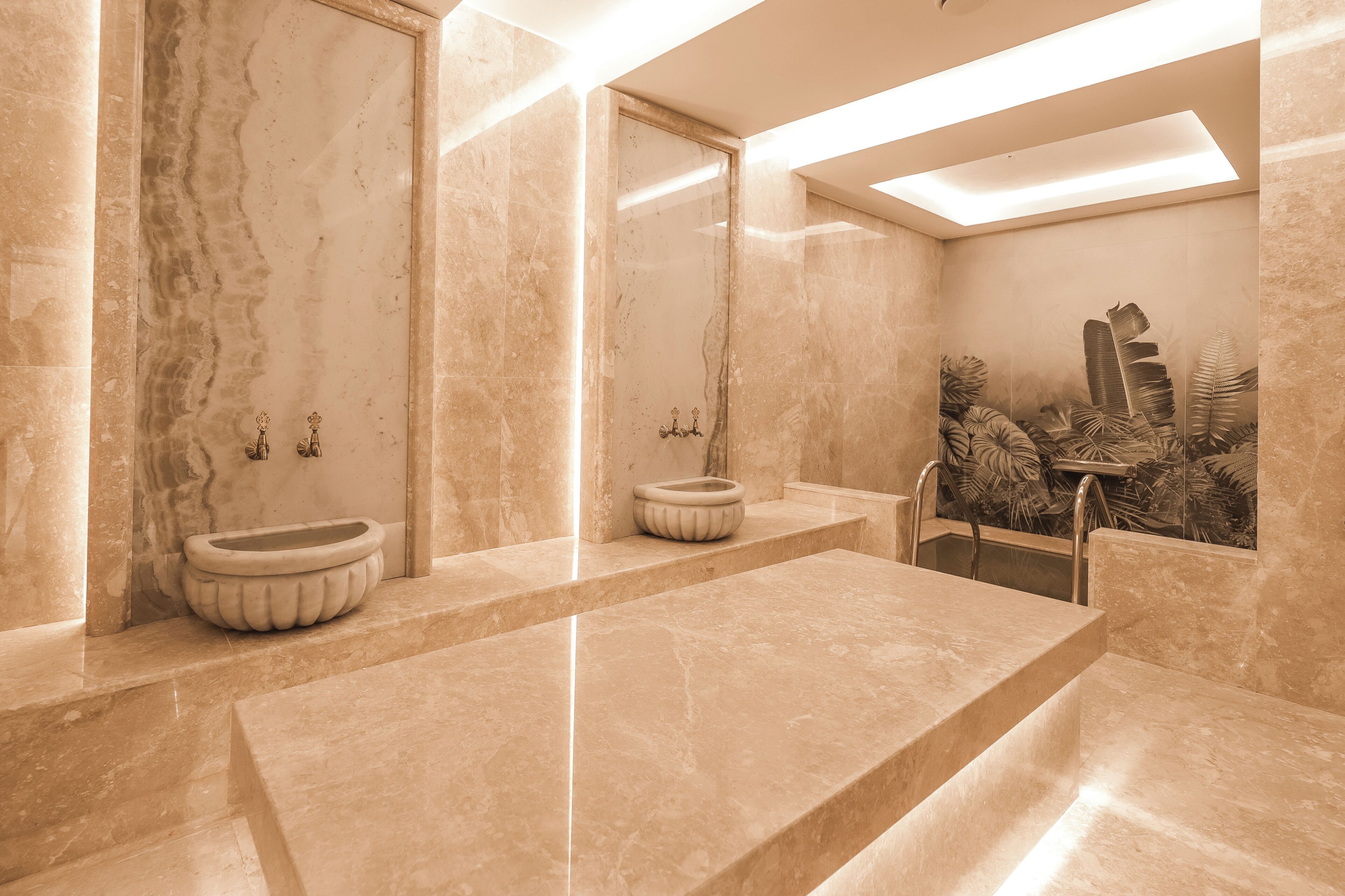 A modern bathroom with marble walls, a large sink, and a decorative plant wall.
