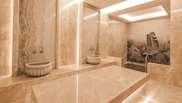 A modern bathroom with marble walls, a large sink, and a decorative plant wall.