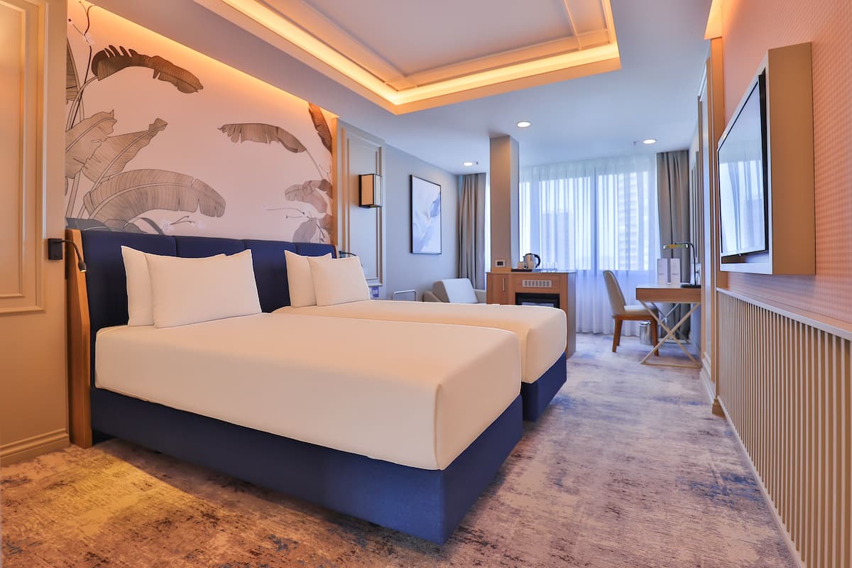 A hotel room with a large bed, a desk, and a TV.