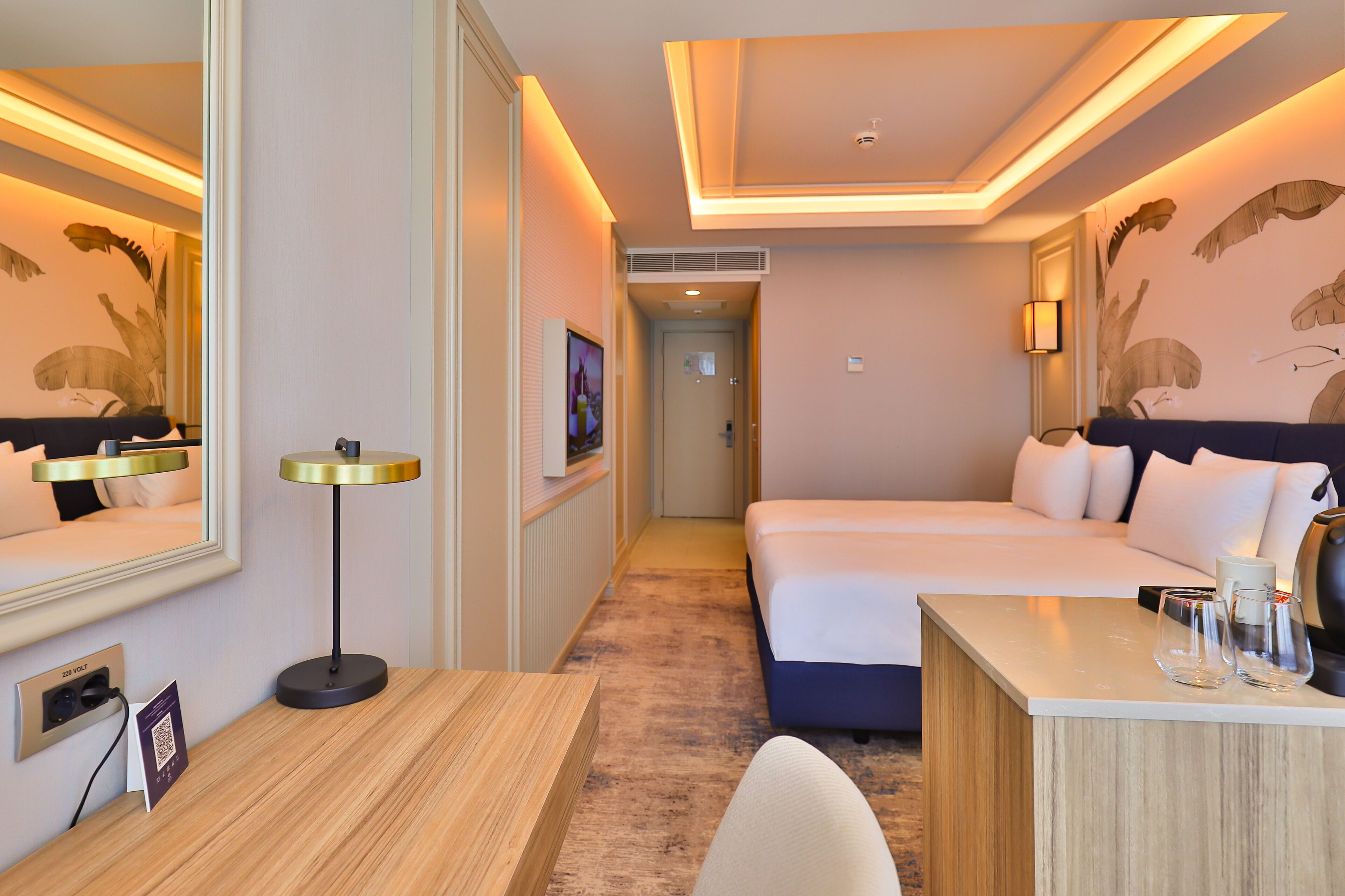 A hotel room with a bed, bedside table, lamp, and a mirror.