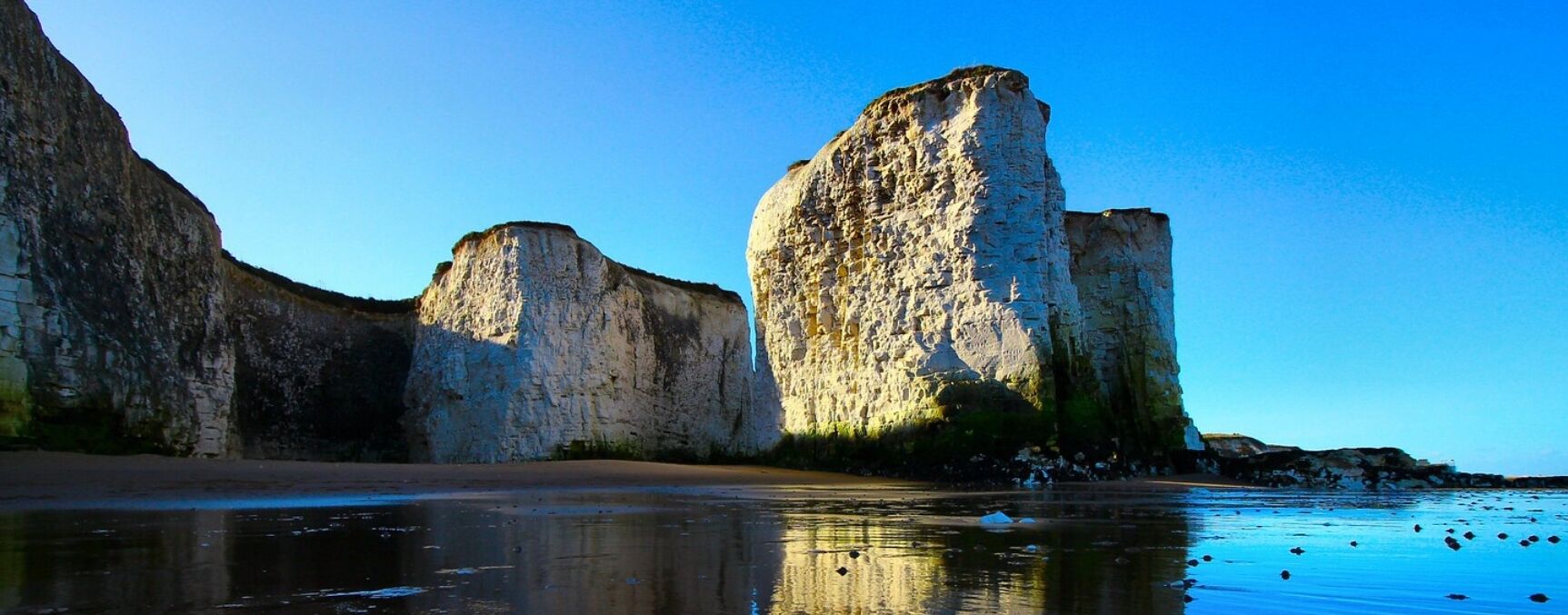 A coastal landscape with large rock formations and a sandy beach.