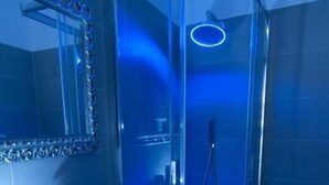 Une salle de bain moderne avec une douche en verre, un lavabo blanc et un miroir doté d’un cadre orné.