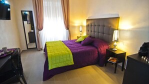 Une chambre d’hôtel comprenant un lit, un bureau, une chaise et une table de chevet avec une lampe.