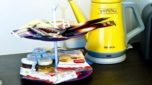Un comptoir de cuisine avec une bouilloire jaune, une assiette contenant des portions de nourriture emballées et des bocaux.