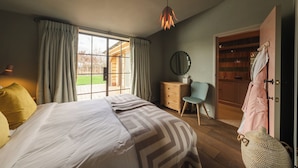A bedroom with a large bed, a desk, a chair, and a wardrobe. - Wilderness Reserve - Newt Cottage (Halesworth)