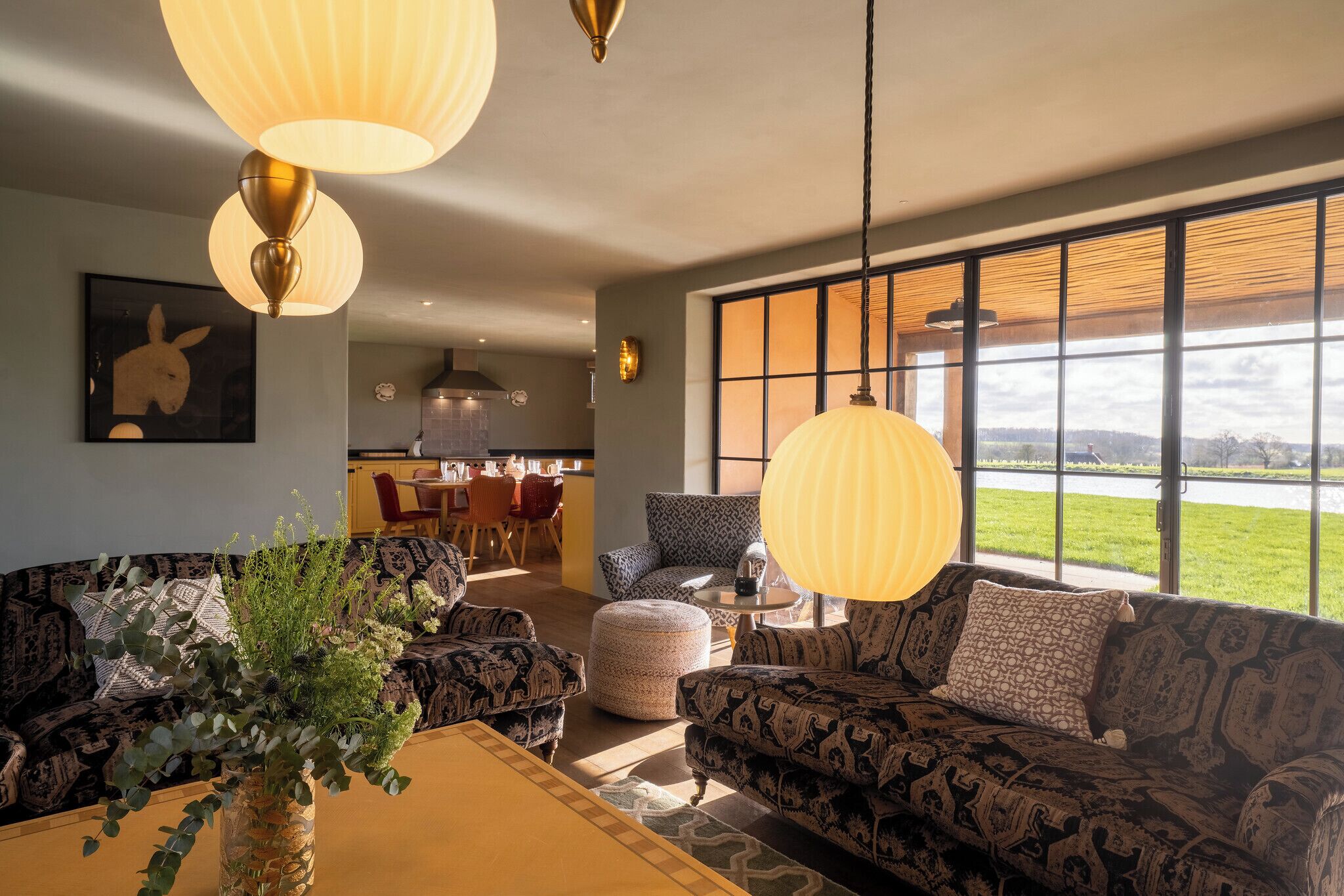 A modern living room with patterned sofas, a coffee table, and a large window with a view of the outdoors.