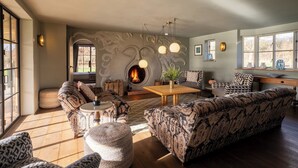 A cozy living room with patterned sofas, a central coffee table, and a fireplace. - Wilderness Reserve - Newt Cottage (Halesworth)
