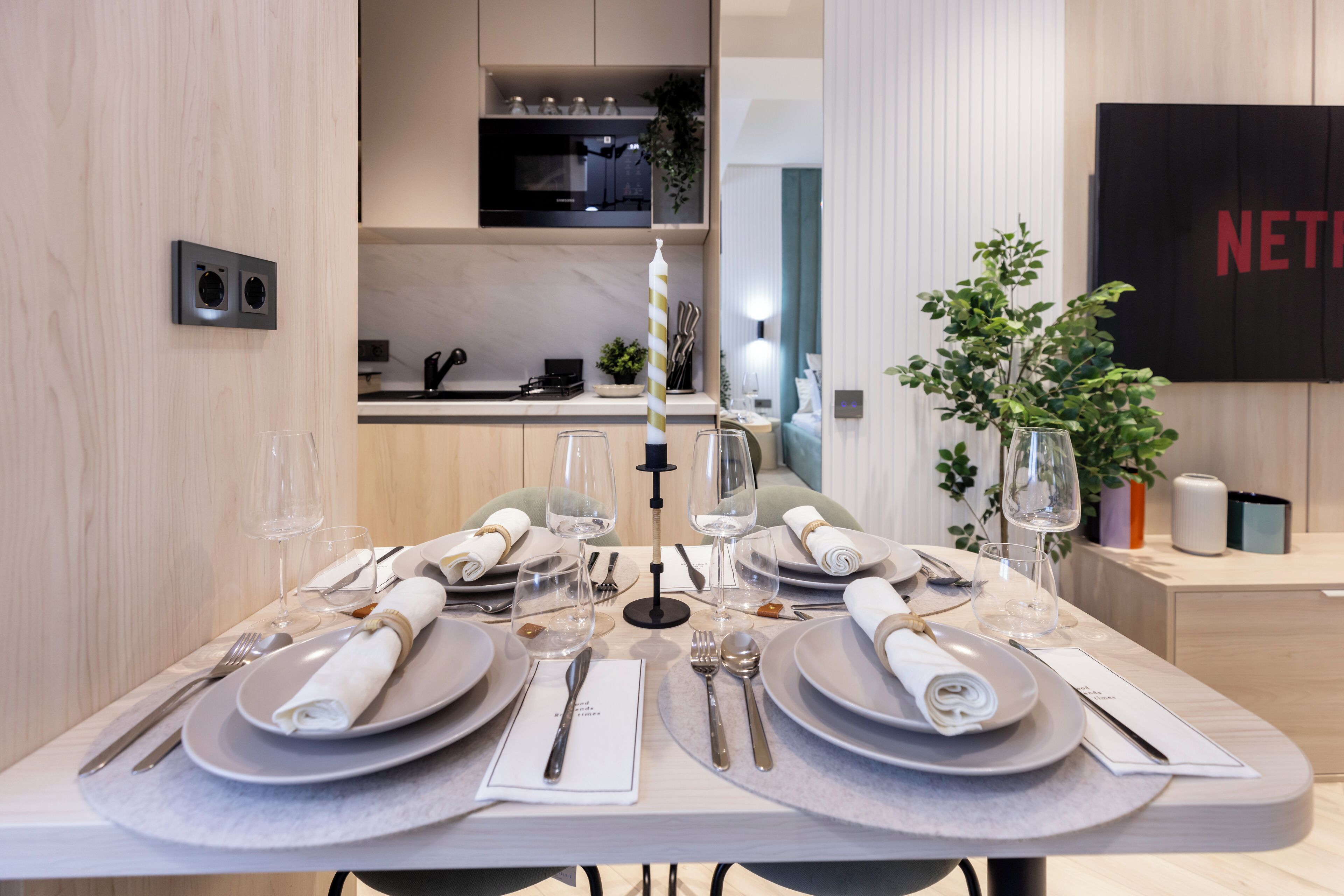 A dining table set with plates, cutlery, and glasses, with a candle centerpiece.