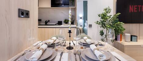 A dining table set with plates, cutlery, and glasses, with a candle centerpiece.