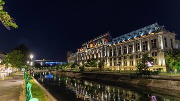 A historic building with classical architecture, a canal in front, and modern lighting.