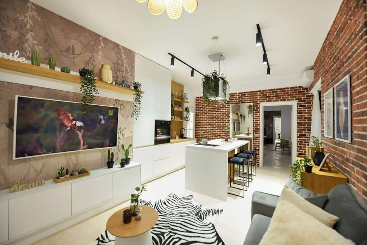 Un salon moderne avec un téléviseur à écran plat, un tapis à motifs zébrés et un mur en briques.