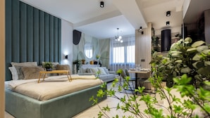A modern bedroom with a large bed, a sofa, and a dining area with a table and chairs. - Aiastay Bucharest River Apartments (Bucharest)