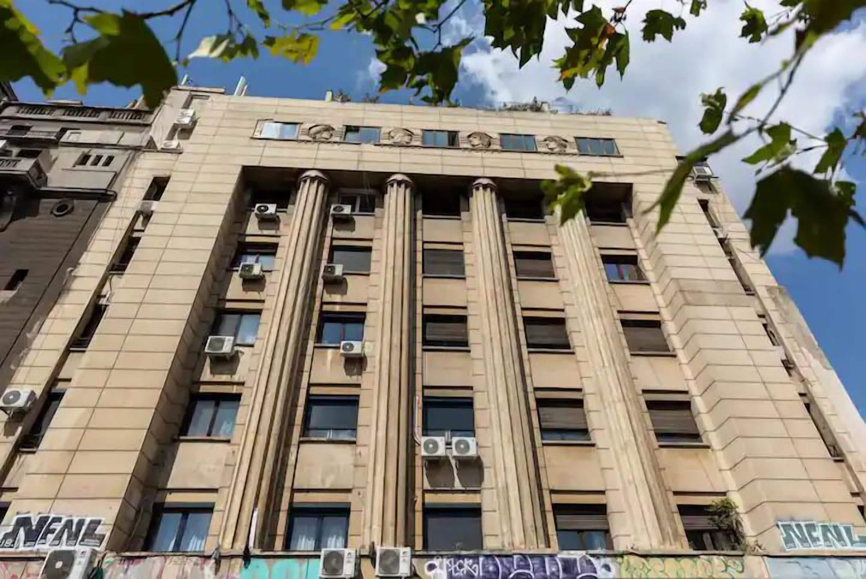 Un edificio alto con múltiples unidades de aire acondicionado, ventanas amplias y un letrero que dice "NEAL".