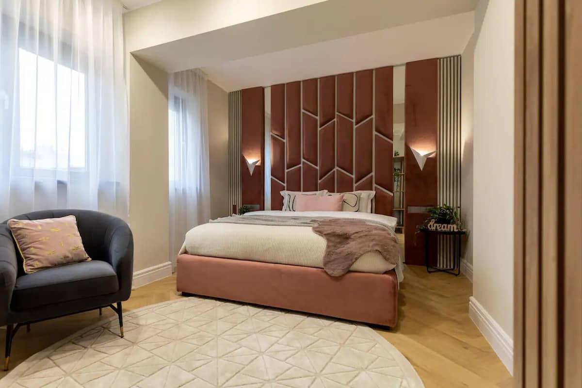 Une chambre moderne avec un grand lit, une chaise et une table de chevet avec une lampe.