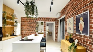 A modern kitchen with a brick wall, white cabinetry, and a central island. - Aiastay Bucharest River Apartments (Bucharest)