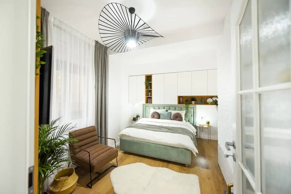 Une chambre moderne avec un lit, une chaise, une petite table et une grande fenêtre.