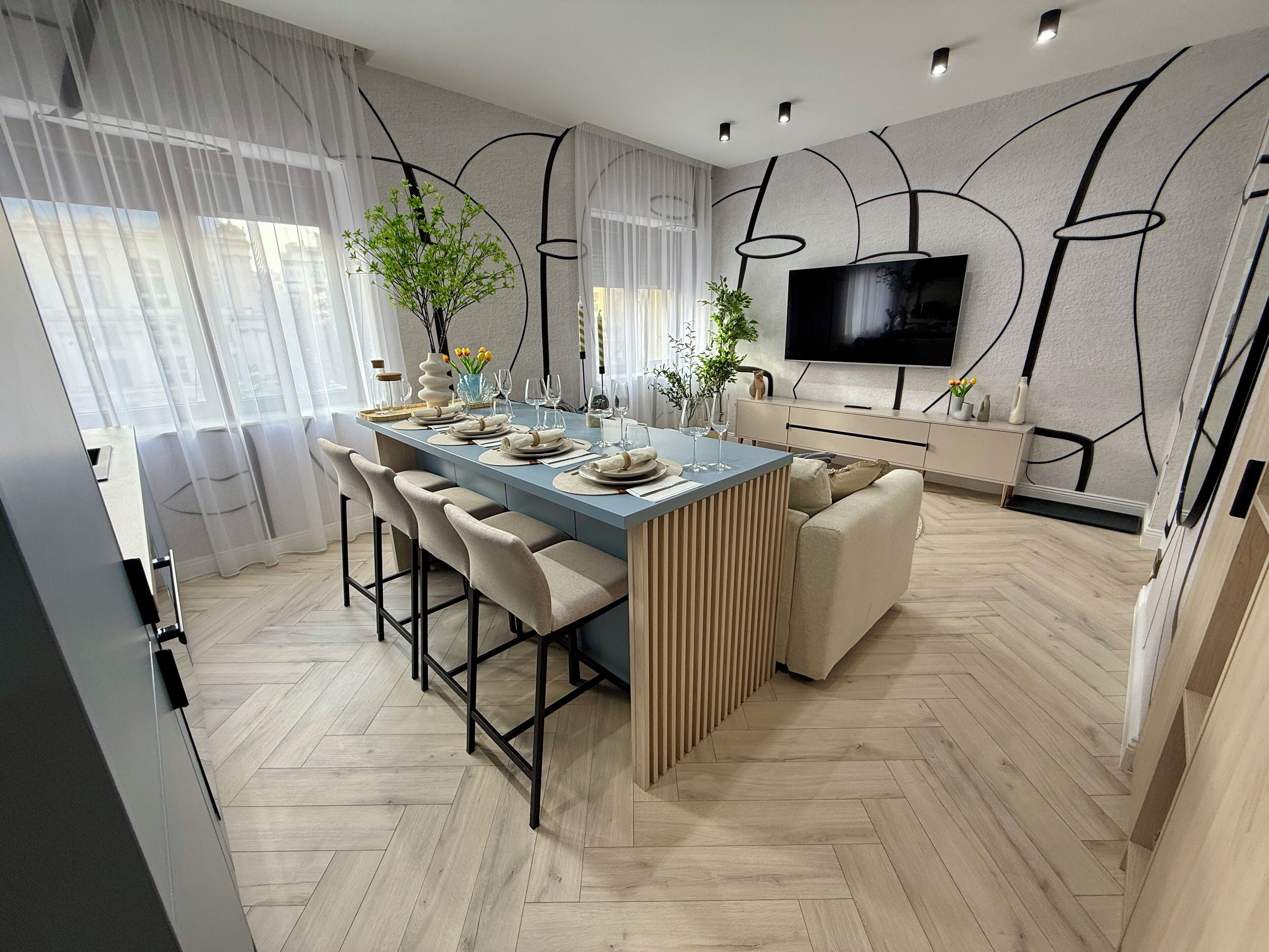 Una cocina moderna con una isla central, taburetes de bar y una mesa de comedor para seis.