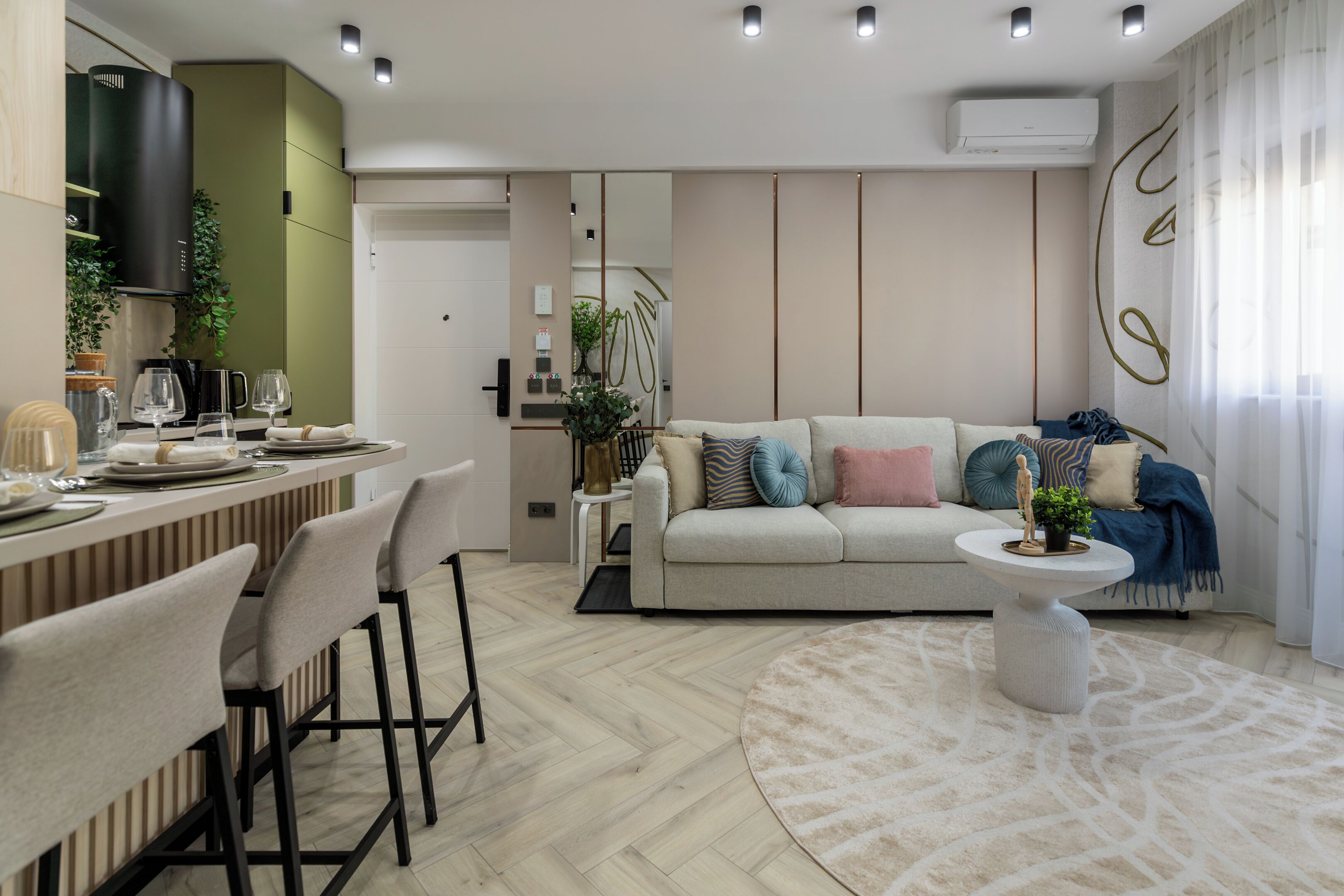 A modern living room with a sofa, coffee table, and dining area with chairs and a bar.
