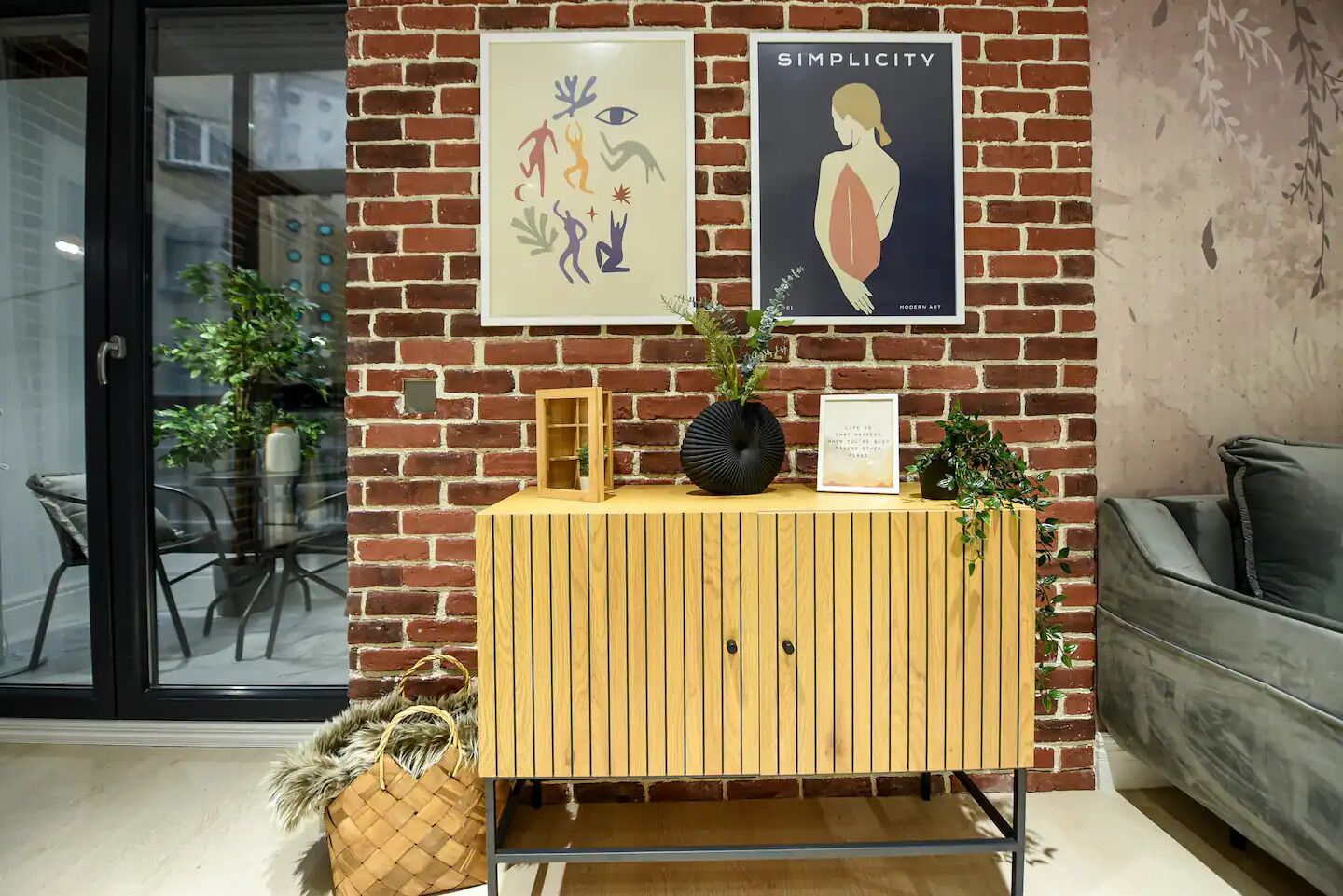 A wooden cabinet with a framed picture, a black vase, and a small plant on top.