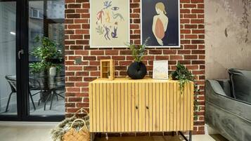 A wooden cabinet with a framed picture, a black vase, and a small plant on top.