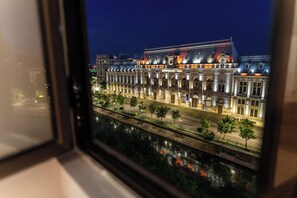 Een historisch gebouw met klassieke architectuur, een rivier ervoor en een uitzicht vanuit een raam.