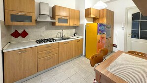 Una cocina con armarios de madera, estufa a gas, pileta y refrigerador colorido.
