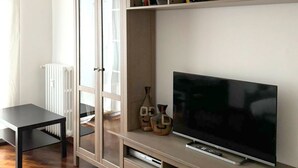 Una sala de estar moderna con un televisor de pantalla plana, una estantería y un radiador.