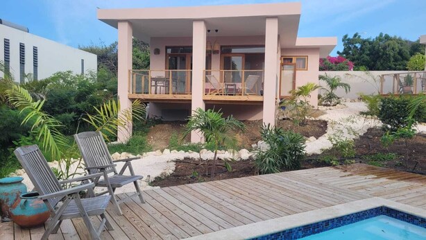 Une maison moderne dotée d’une piscine, d’une terrasse en bois et d’un espace salon extérieur.