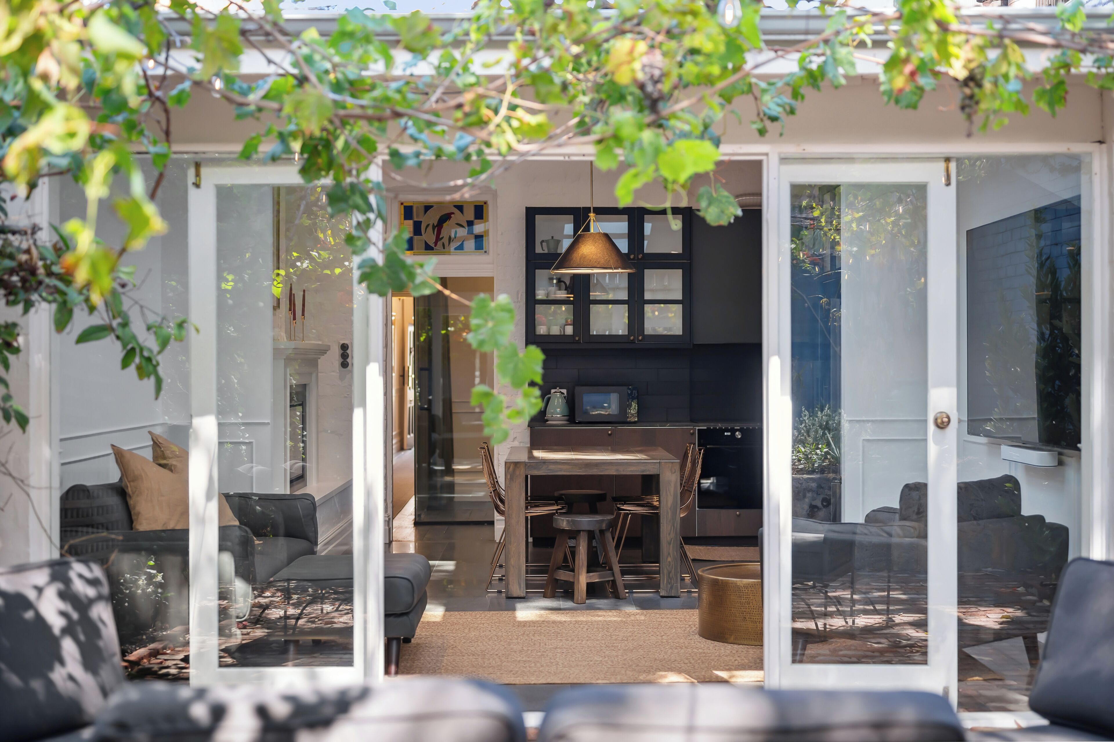 A modern kitchen with a dining area, featuring a wooden table and chairs, and a hanging pendant light.