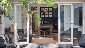 A modern kitchen with a dining area, featuring a wooden table and chairs, and a hanging pendant light. - Paton House, Beach 250m | Heritage Luxe w/ Fireplace and 86" TV (South Fremantle)