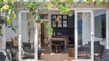 A modern kitchen with a dining area, featuring a wooden table and chairs, and a hanging pendant light.