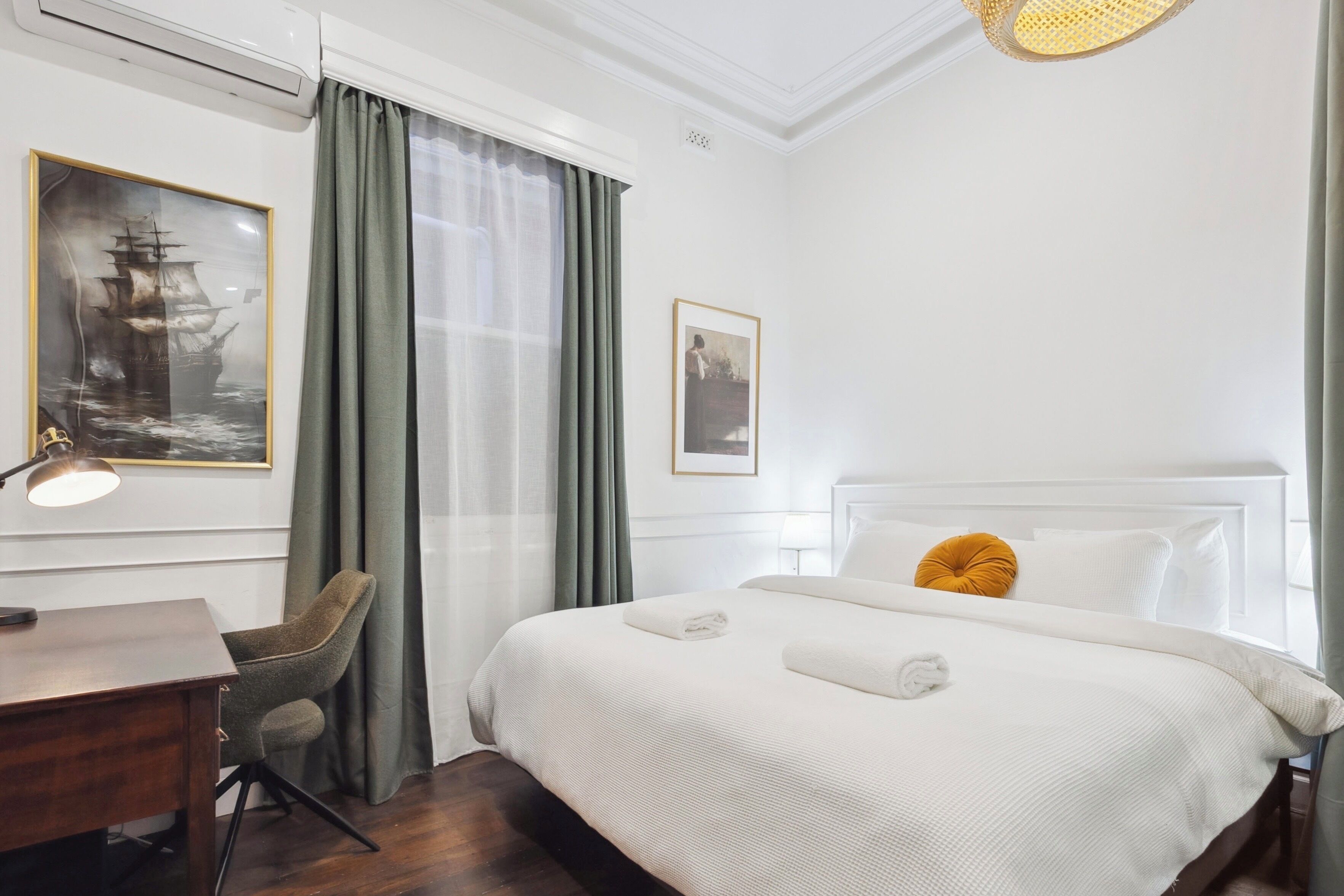 Camera d'albergo con un letto grande, una scrivania, una sedia e una finestra con tende.