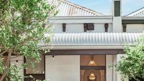 A white building with a tiled roof, a brick entrance, and a small staircase leading to a hallway with a chandelier. - Paton House, Beach 250m | Heritage Luxe w/ Fireplace and 86" TV (South Fremantle)